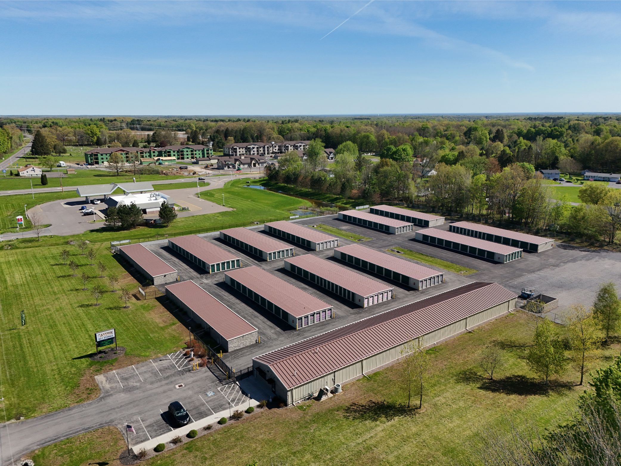 Aerial view of A-Verdi Self Storage Baldwinsville facility with multiple storage buildings, paved driveways, and surrounding green landscape.